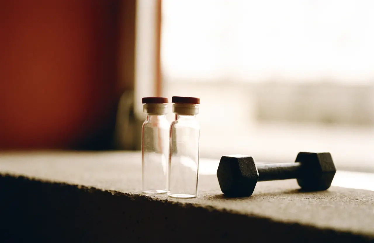 Two empty blood collection vials beside a small dumbbell