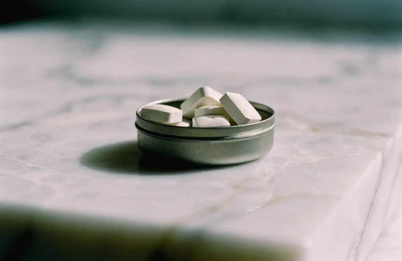An open metal tin of soft chewable tablets on a marble surface